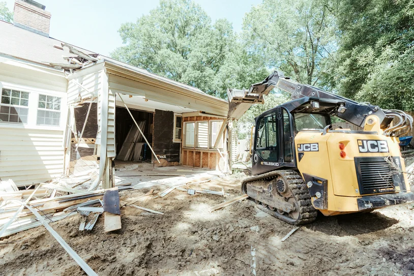 Mini excavator demolishing the exterior wall of a house during a renovation