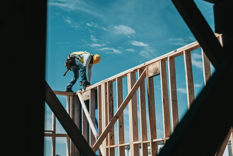 Construction worker securing roof framing high on a wood-framed structure