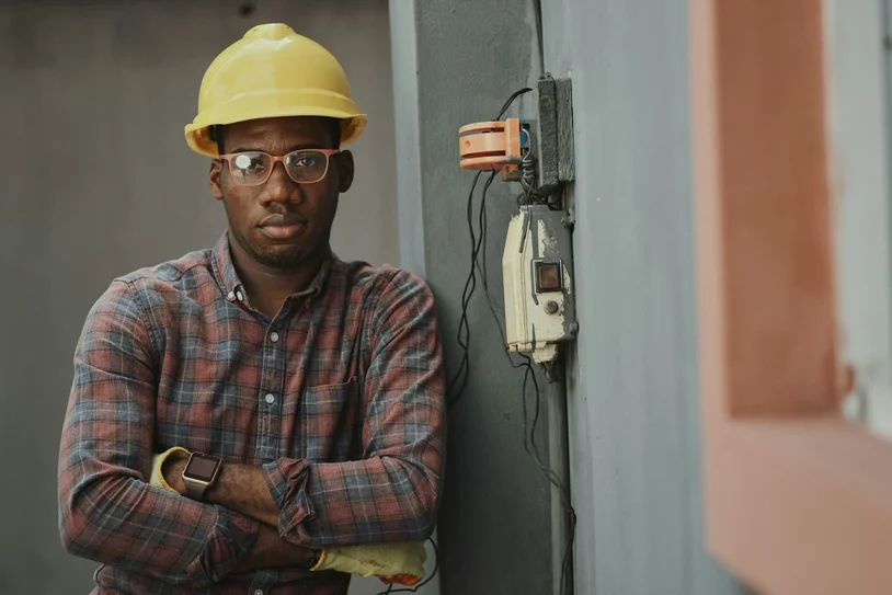 Construction worker in hard hat standing with arms crossed on a job site