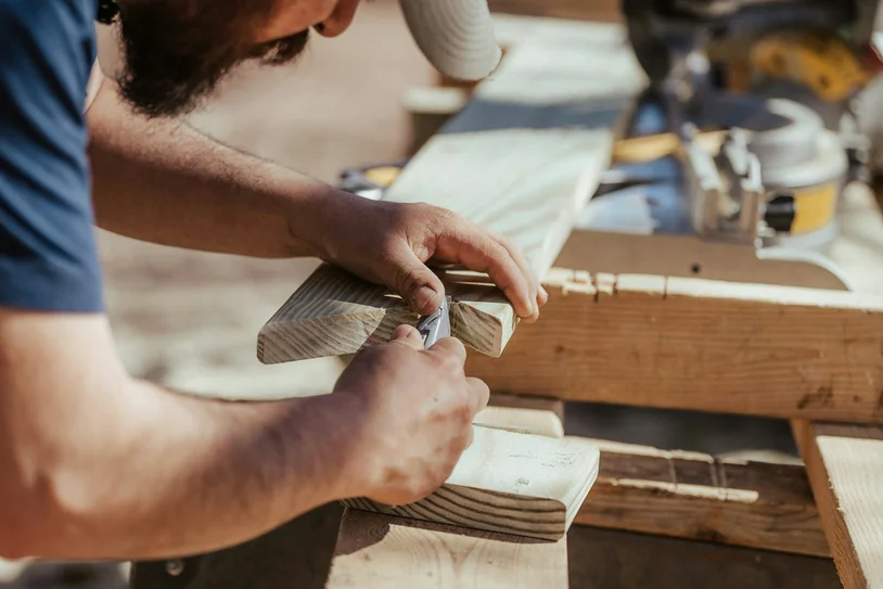 Close-up of a carpenter's hands shaping a wooden board with a hand plane