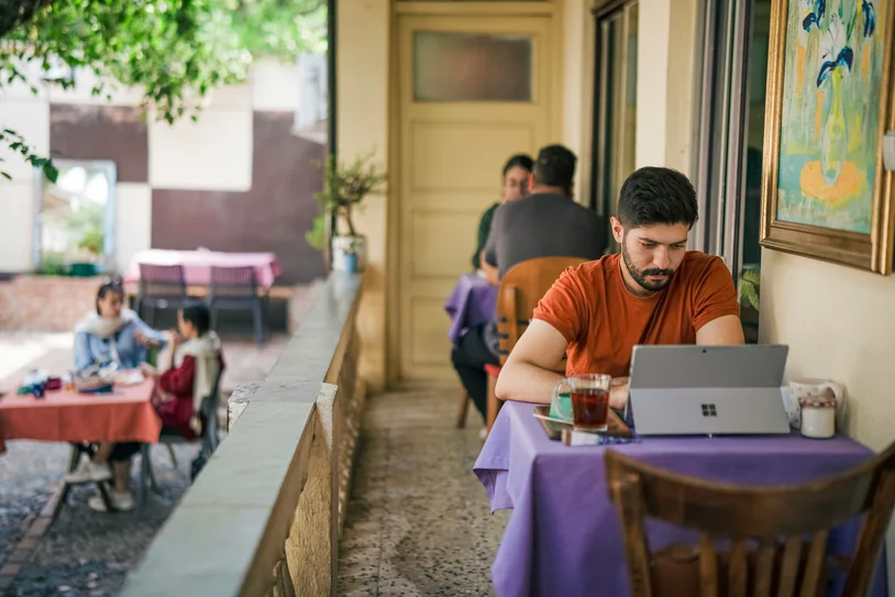 Person working on a laptop at an outdoor cafe terrace table