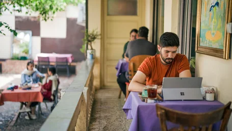 Person working on a laptop at an outdoor cafe terrace table
