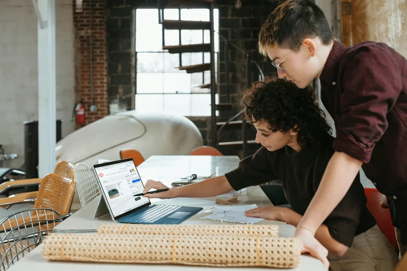 Two people collaborating while looking at a laptop screen together
