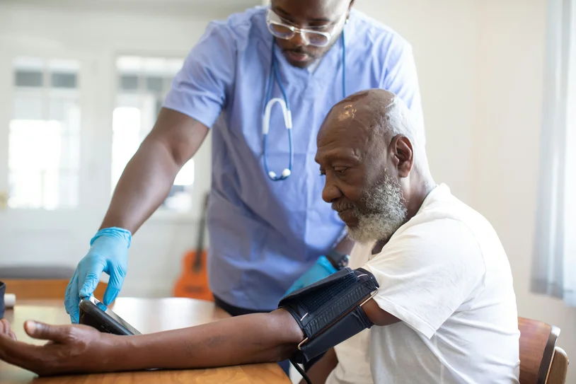 Nurse checking an elderly patient's blood pressure during a home visit