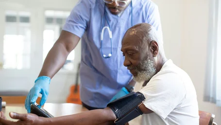 Nurse checking an elderly patient's blood pressure during a home visit