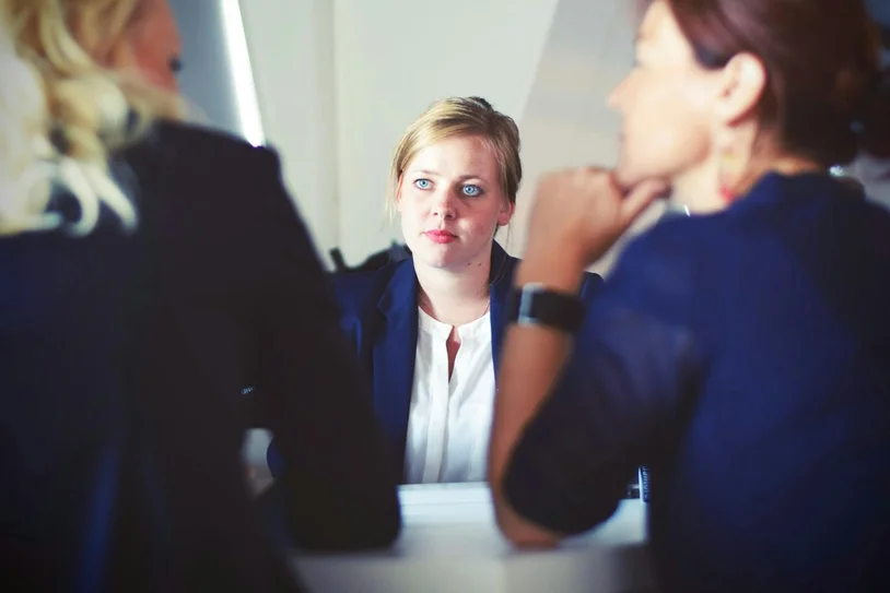 Woman attentively listening during a meeting with two colleagues in business attire