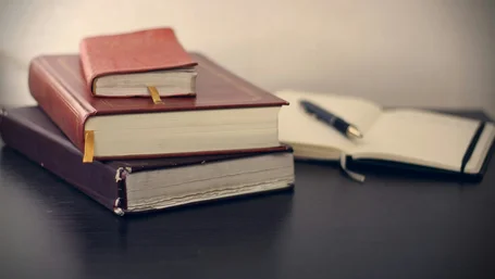 Stack of leather-bound legal books beside an open notebook and pen