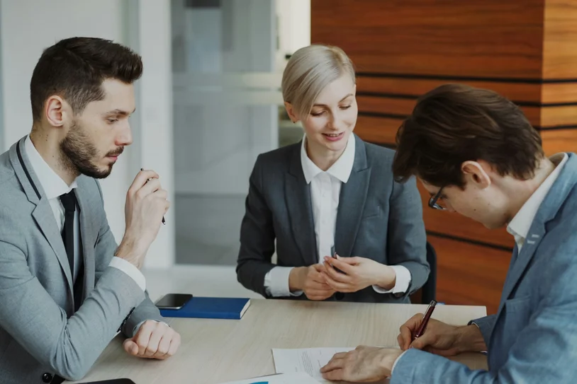Three attorneys in suits reviewing documents together at a conference table