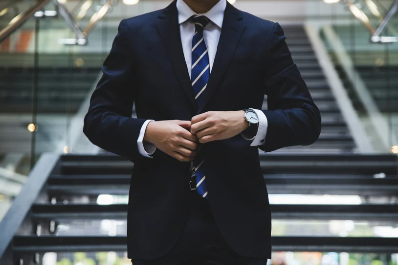 Attorney in a navy suit adjusting his jacket while wearing a wristwatch