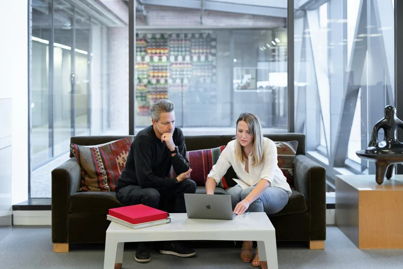 Two colleagues reviewing information together on a laptop in a modern office