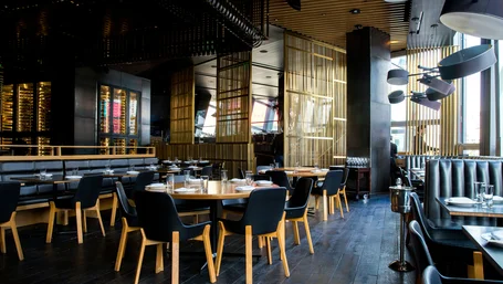 Upscale restaurant dining room with set tables and pendant lighting