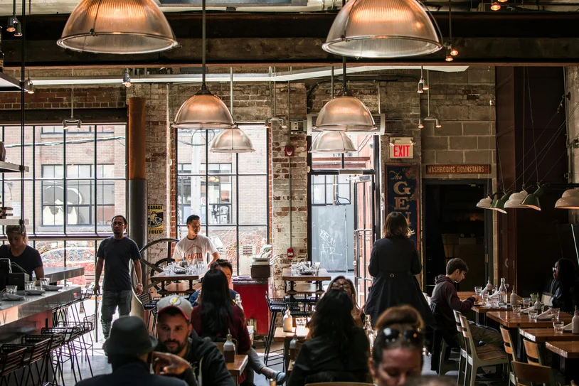 Crowded industrial-style restaurant full of diners and staff