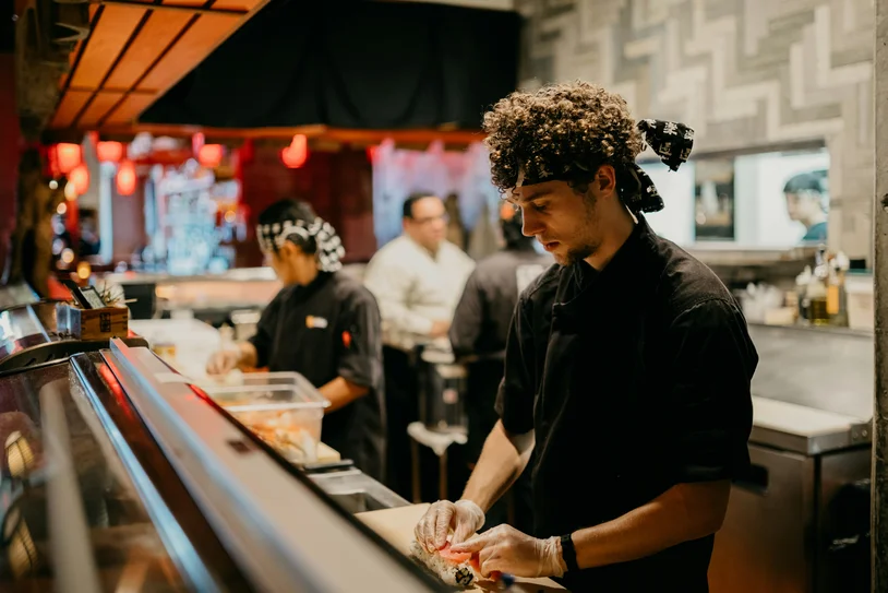 Chef preparing food behind the counter of a busy restaurant kitchen