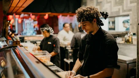 Chef preparing food behind the counter of a busy restaurant kitchen