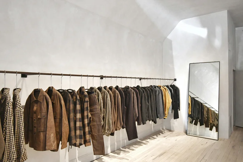 Minimalist clothing rack with curated jackets and shirts in a sunlit boutique