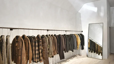 Minimalist clothing rack with curated jackets and shirts in a sunlit boutique
