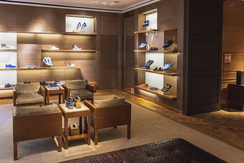 Lounge seating area beside a backlit shoe display wall in a boutique
